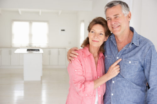 A man and woman laying in bed smiling for the camera.