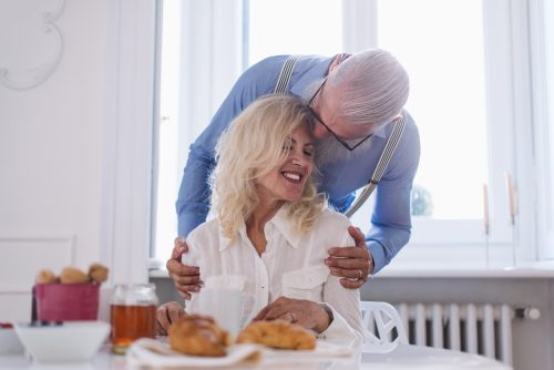 A man and woman laying in bed smiling for the camera.