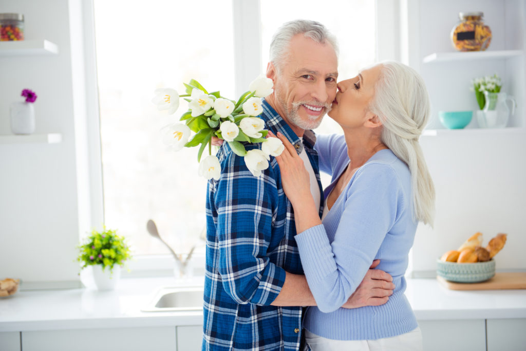 A man and woman laying in bed smiling for the camera.