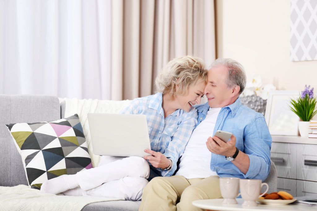 A man and woman laying in bed smiling for the camera.