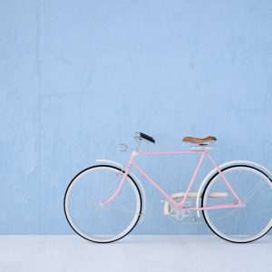 A pink bicycle is parked against the wall.