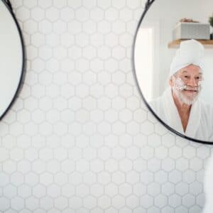 A man with a towel on his head is in the mirror.