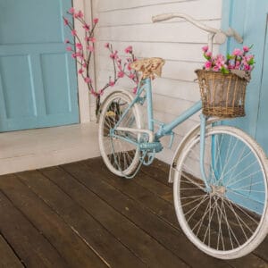A bicycle with flowers in the basket on the front of it.