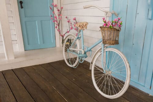 A bicycle with flowers in the basket on the front of it.
