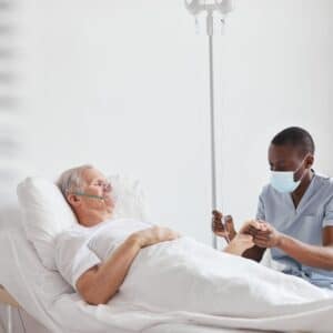 A nurse is helping an older man in hospital.
