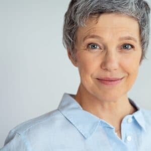 A woman with grey hair wearing a blue shirt.