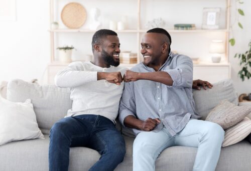 A man and woman laying in bed smiling for the camera.