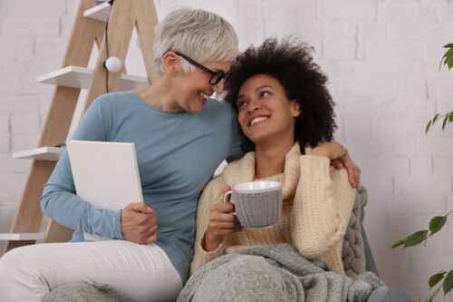 A man and woman laying in bed smiling for the camera.