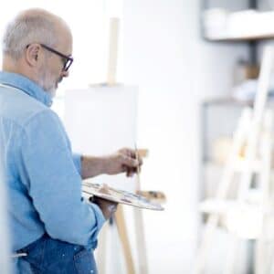 A man painting on canvas in an art studio.