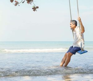 A man swinging on a rope swing in the water.