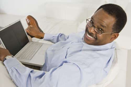 A man and woman laying in bed smiling for the camera.