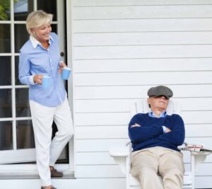 A woman standing next to an older man on a porch.
