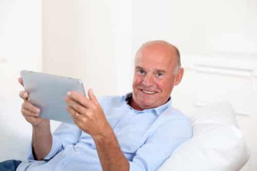 A man and woman laying in bed smiling for the camera.