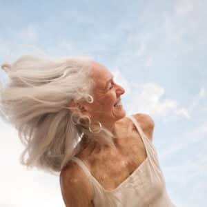 A woman with long white hair is smiling.