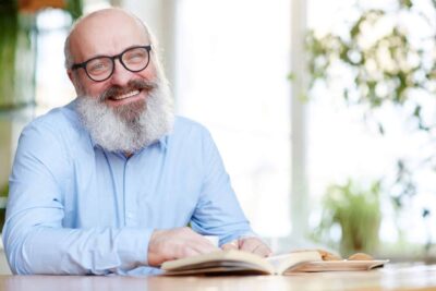 A man with glasses is reading a book