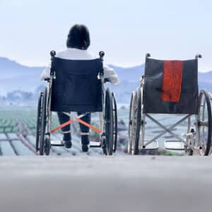 A person in a wheelchair is sitting on the ground