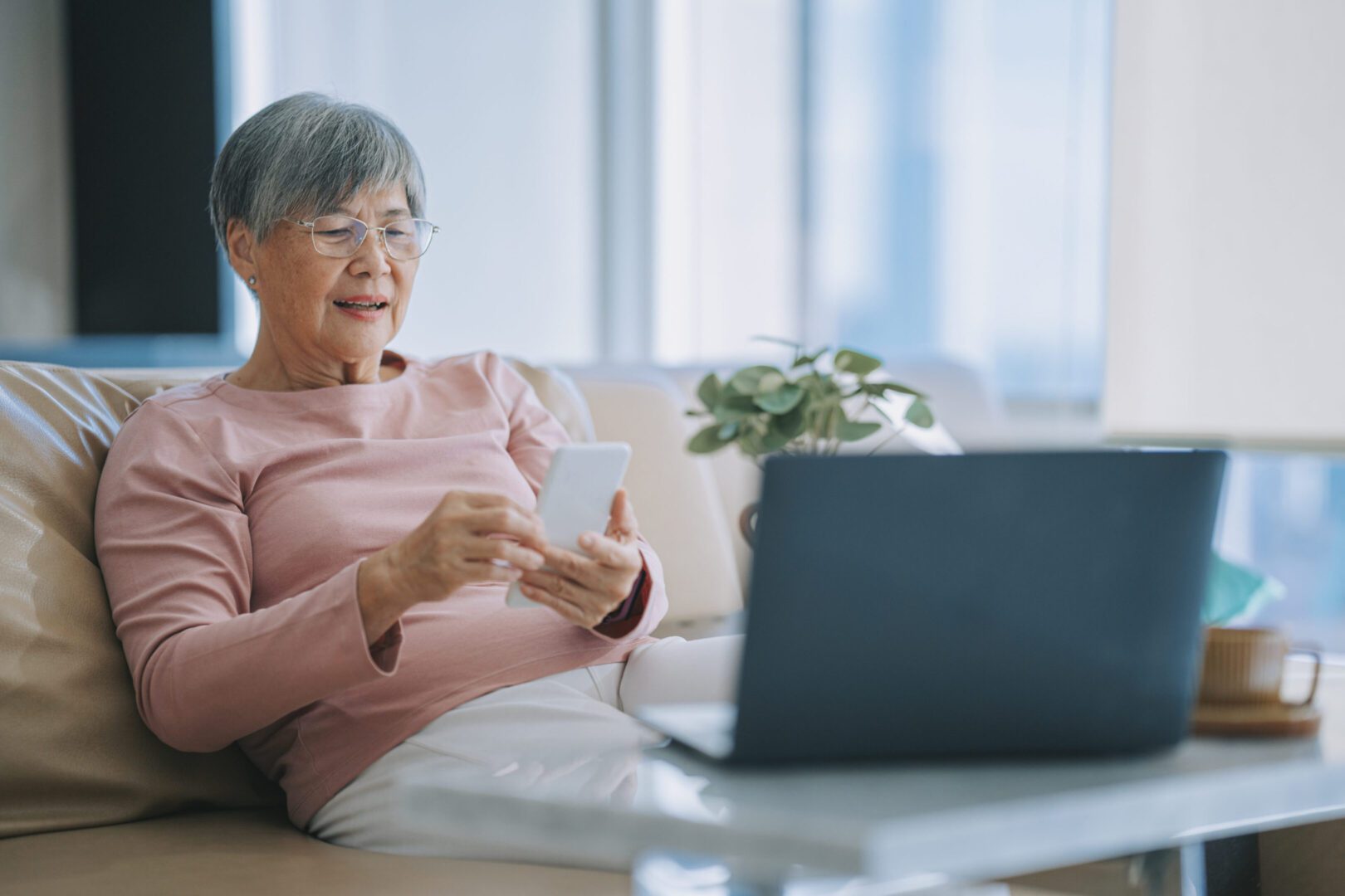 Senior woman using smartphone on sofa
