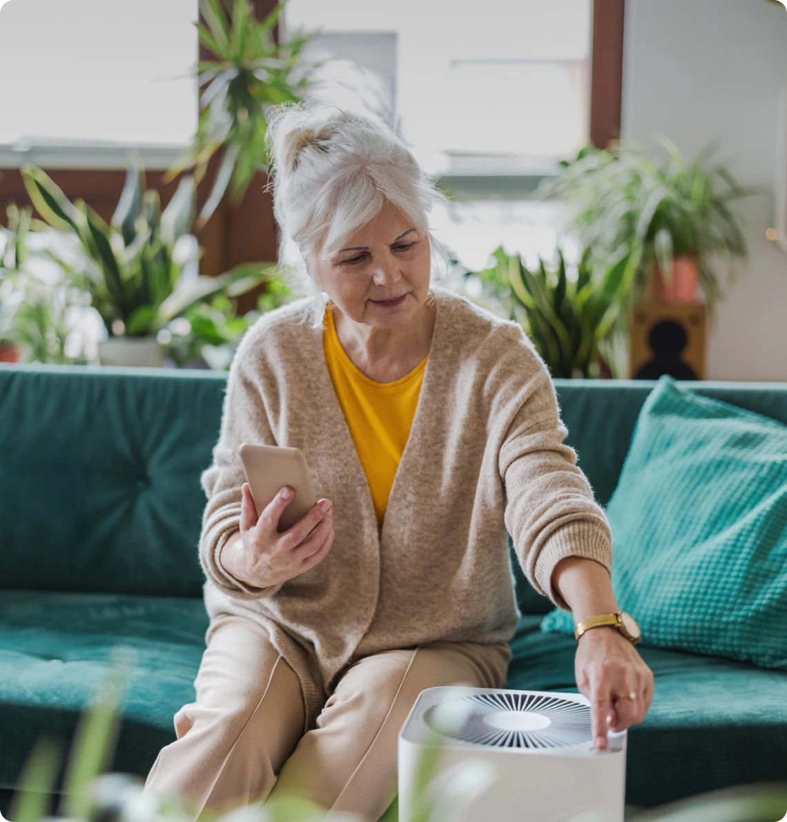 Elderly lady with air purifier and phone